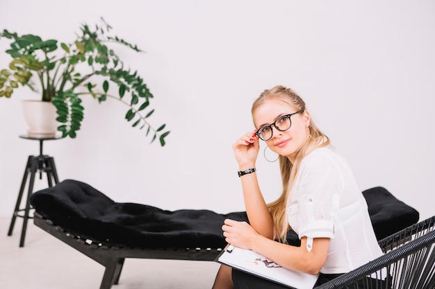 Zdjęcie uśmiechnięty portret piękny psychologa obsiadanie na krześle z schowkiem w biurze