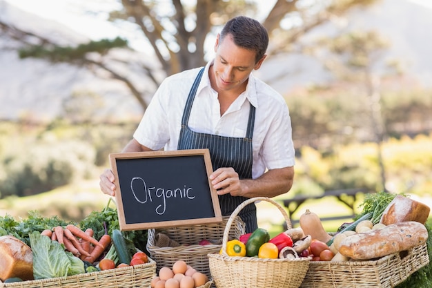 Uśmiechnięty rolnik trzyma organicznie znaka