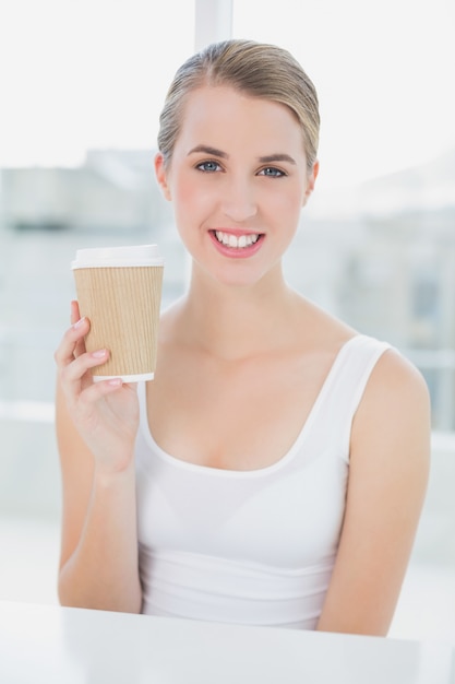Uśmiechnięty śliczny blondynki mienia kubek kawa