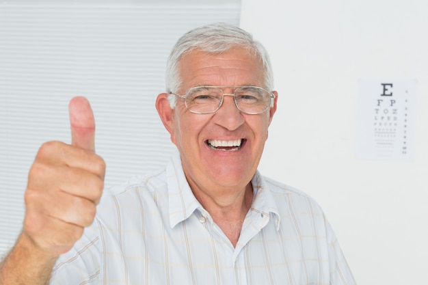 Uśmiechnięty starszy mężczyzna gestykuluje aprobaty z oko mapą w tle