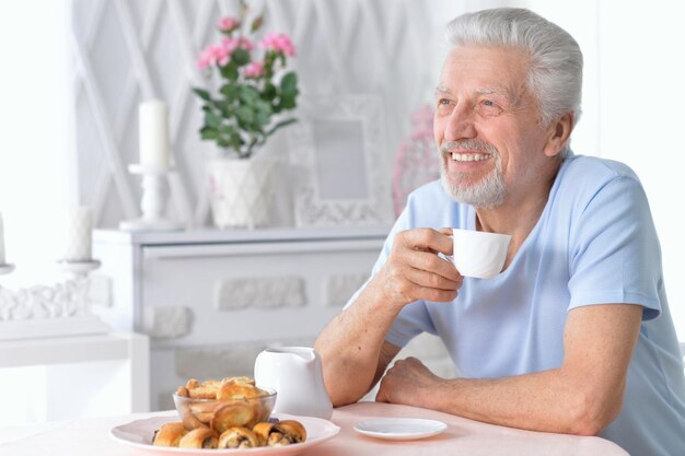 Uśmiechnięty starszy mężczyzna pijący herbatę w domu