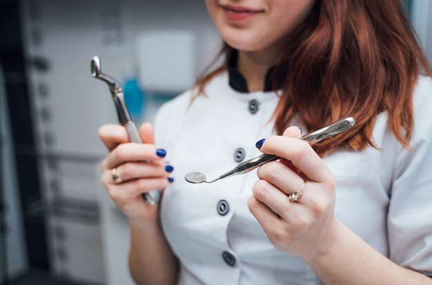 Zdjęcie uśmiechnięty stomatolog trzyma nierdzewnego wyposażenie w klinice dentystycznej. instrumenty medyczne w rękach profesjonalnego lekarza w białym mundurze.