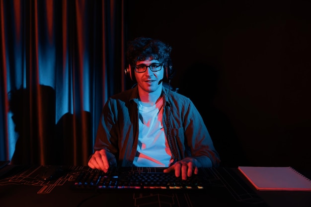 Uśmiechnięty streamer z joystickem skupiający drużynę esportową na komputerze z mocniejszym strumieniem