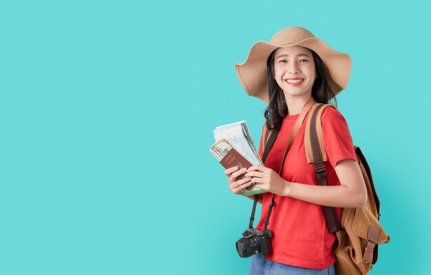 Uśmiechnięty szczęśliwie Azjatycki kobieta podróżnika mienia paszport z biletem i mapą, pieniądze na błękicie.
