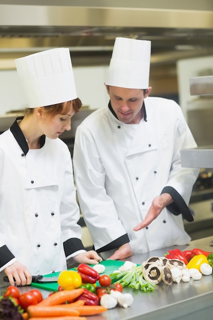 Uśmiechnięty szef kuchni patrzeje jego koledze pokrojone pieczarki