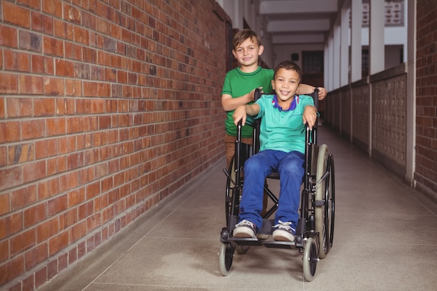 Uśmiechnięty uczeń na wózku inwalidzkim i przyjaciel obok niego