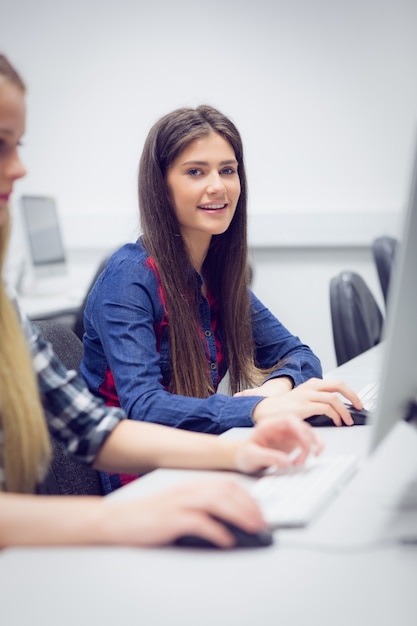 Uśmiechnięty uczeń pracuje na komputerze przy uniwersytetem