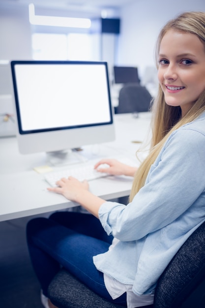 Uśmiechnięty uczeń pracuje na komputerze przy uniwersytetem