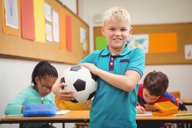 Uśmiechnięty uczeń trzyma futbol