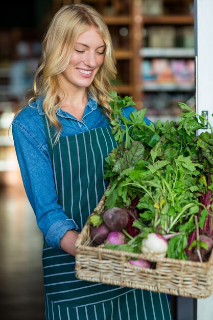 Uśmiechnięty żeński personel trzyma kosz świeżych warzywa