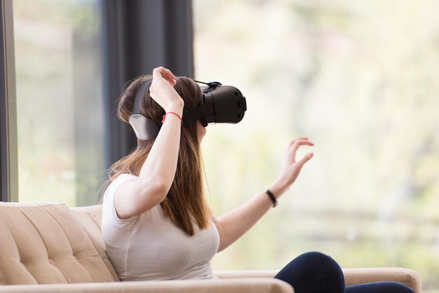 Uśmiechnij się szczęśliwą kobietą, która zdobywa doświadczenie w korzystaniu z okularów wirtualnej rzeczywistości VR w domu