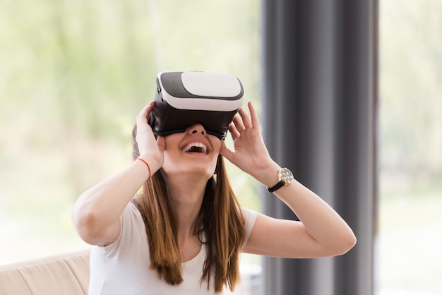 Uśmiechnij się szczęśliwą kobietą, która zdobywa doświadczenie w korzystaniu z okularów wirtualnej rzeczywistości VR w domu
