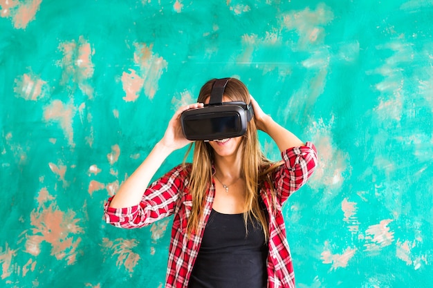 Uśmiechnij się szczęśliwą kobietą zdobywającą doświadczenie za pomocą okularów wirtualnej rzeczywistości wirtualnej rzeczywistości w domu, dużo gestykulując rękami.