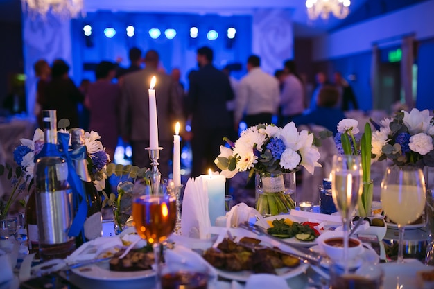 Ustawienia stołu weselnego w restauracji. Ludzie tańczący w tle stołu dla nowożeńców.