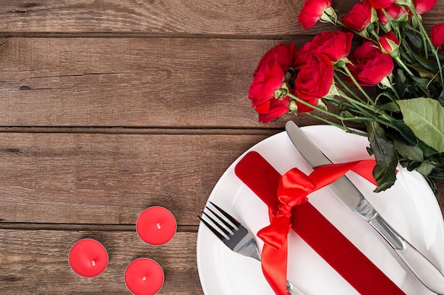 Ustawienie stołu Walentynki z talerzem, prezentem, czerwoną wstążką i różami. Walentynki-dzień tło. Martwa natura