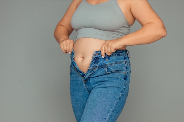 utrata wagi i problem z nadwagą gruba kobieta w podkoszulku i dżinsach próbuje zapiąć guziki lub pu