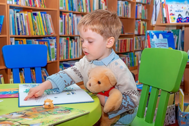 Uważne dziecko studiuje i siedzi w czytelni biblioteki