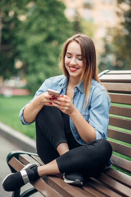 Uzależnienie od telefonu, uzależniona kobieta korzystająca ze smartfona na ławce w parku, ludzie uzależnieni od społeczeństwa