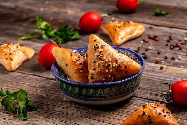 Uzbeckie danie narodowe samosa Indyjskie samosy pieczone ciasto z pikantnym nadzieniem popularne indyjskie przekąski podawane w misce z przyprawami na rustykalnym tle widok z góry