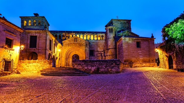 Uzyskaj dostęp do esplanady do średniowiecznego kościoła oświetlonego nocą latarniami ulicznymi. Santillana del Mar.