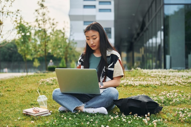 Używa laptopa Młoda azjatycka kobieta jest na zewnątrz w ciągu dnia