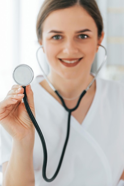Używanie stetoskopu Młoda pielęgniarka stoi w biurze