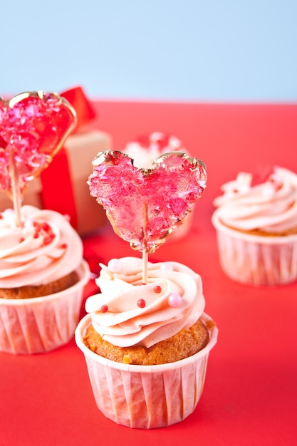 Valentines cupcake cream cheese frosting ozdobione lizakiem candy heart i pudełko na tle.