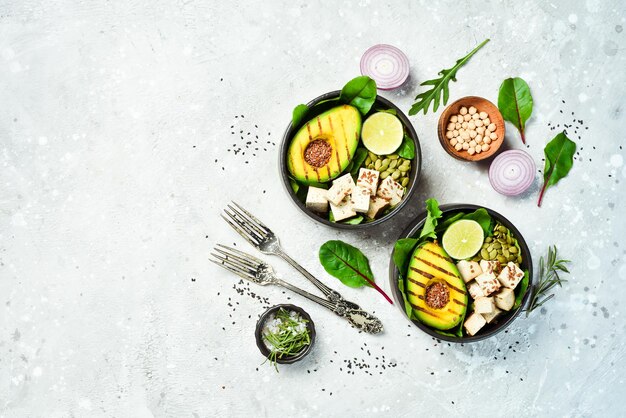 Zdjęcie vegan buddha bowl awokado tofu ser len pestki dyni i szpinak pojęcie zdrowego odżywiania na kamiennym tle widok z góry