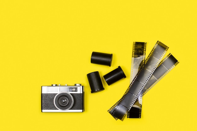 Vintage aparat fotograficzny i negatywy filmowe na żółtym tle z miejscem na kopię