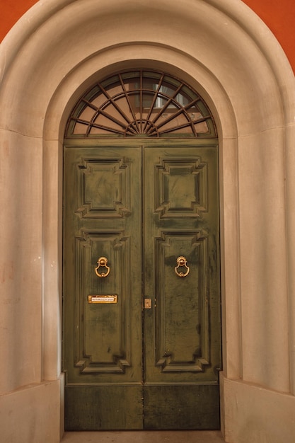 Vintage brązowe zielone drewniane drzwi z pomarańczową ścianą we Włoszech