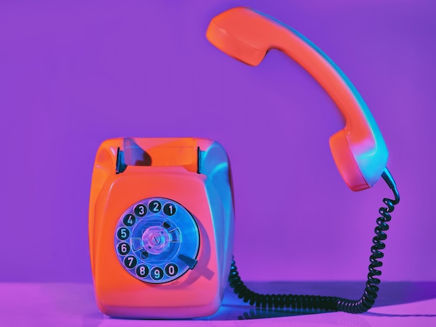 Vintage pomarańczowy telefon w neonowym świetle