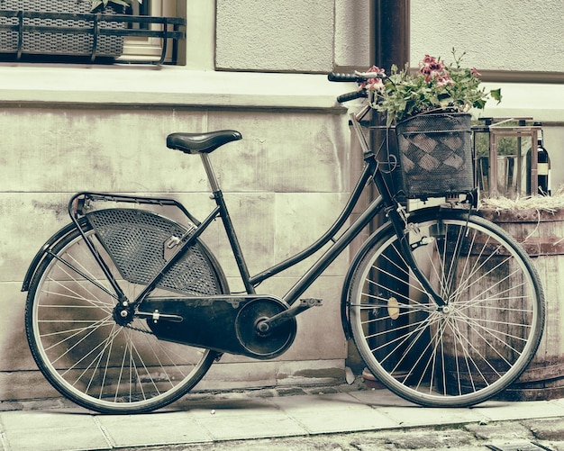 Vintage stylizowane zdjęcie starego roweru niosącego kwiaty jako dekorację