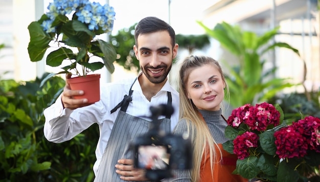 Zdjęcie vlogger ogrodnik pokazujący kamerze kwiat hortensji