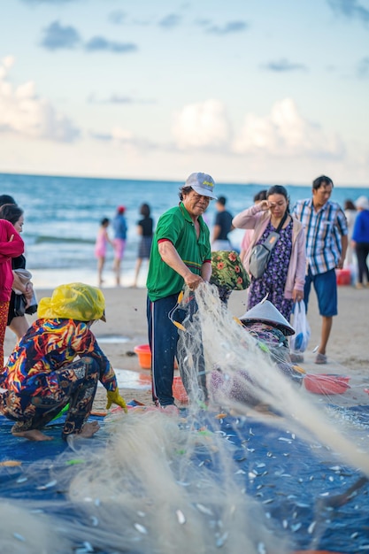 Vung Tau WIETNAM 14 MAJA 2023 Rybak zarzuca sieć o wschodzie lub zachodzie słońca Tradycyjni rybacy przygotowują sieć rybacką