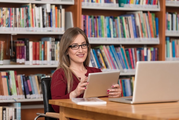 W Bibliotece Piękna Studentka Z Laptopem I Książkami Pracująca W Bibliotece Uniwersyteckiej Płytka głębia ostrości