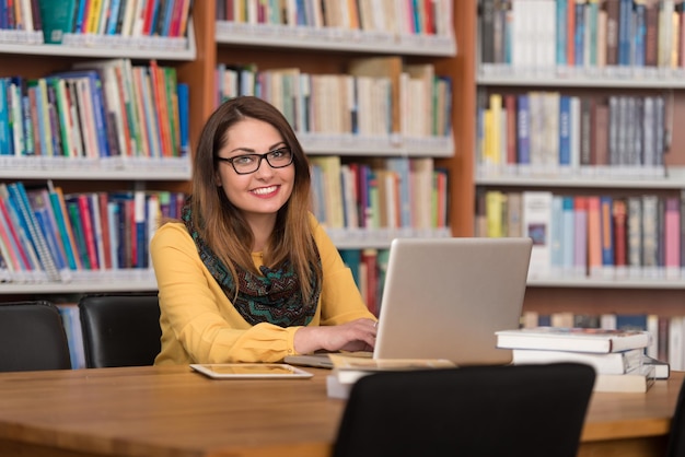 W Bibliotece Piękna Studentka Z Laptopem I Książkami Pracująca W Bibliotece Uniwersyteckiej Płytka głębia ostrości