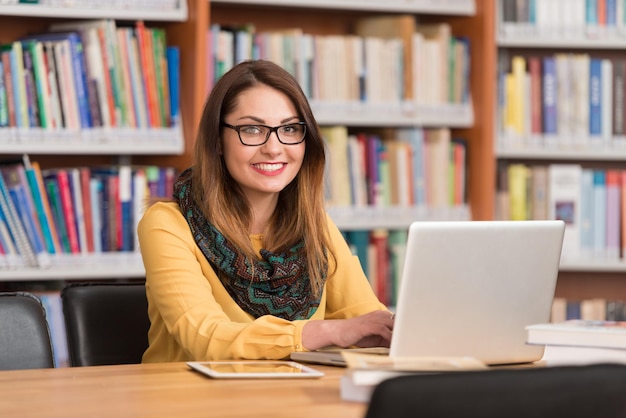 W Bibliotece Piękna Studentka Z Laptopem I Książkami Pracująca W Bibliotece Uniwersyteckiej Płytka głębia ostrości