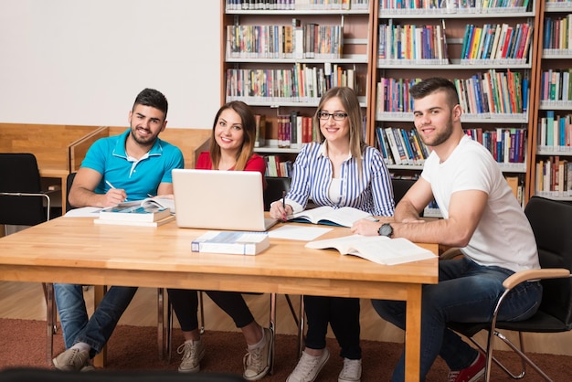 W Bibliotece Przystojna Grupa Uczniów Z Laptopem I Książkami Pracującymi W Bibliotece Uniwersyteckiej Szkoły Średniej Płytkiej głębi ostrości