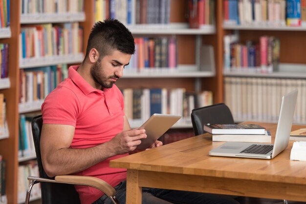 W Bibliotece Przystojny Arabski Student z Laptopem I Książkami Pracujący W Bibliotece Uniwersyteckiej Szkoły Średniej Płytkiej głębi ostrości