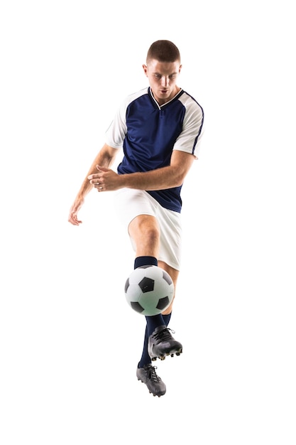 Zdjęcie w całej długości młody kaukazyjski sportowiec kopie piłkę nożną na białym tle