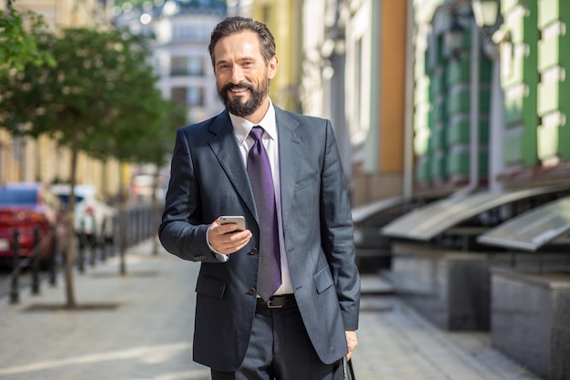 W Drodze Do Pracy. Wesoły Biznesmen Dorosłych Posiadających Telefon Idąc Do Pracy