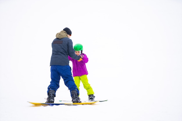 W Dzień Zimnego Windera w Mountain Ski Resort Ojciec uczy córeczkę na snowboardzie