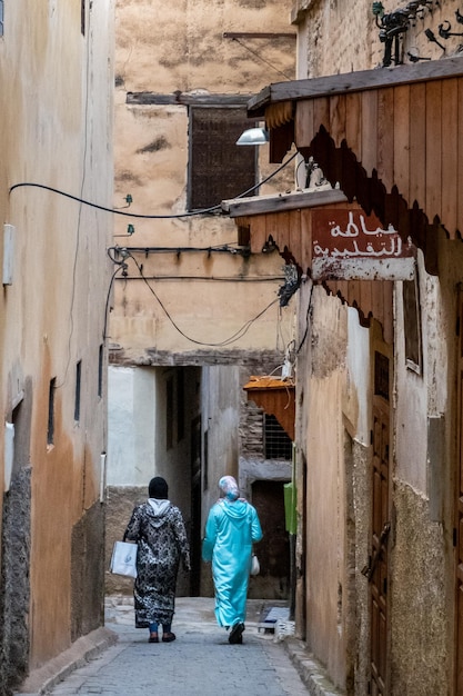 W medynie Fezu w Maroku Dwie zawoalowane kobiety idą wąską uliczką