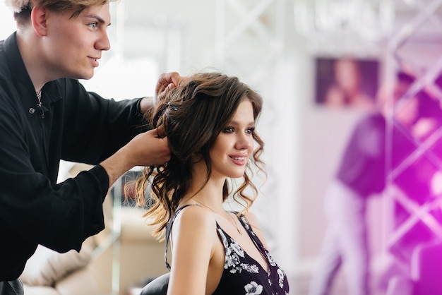 Zdjęcie w pięknym, nowoczesnym salonie kosmetycznym profesjonalna stylistka wykonuje fryzurę i fryzurę dla młodej dziewczyny. piękno i moda.