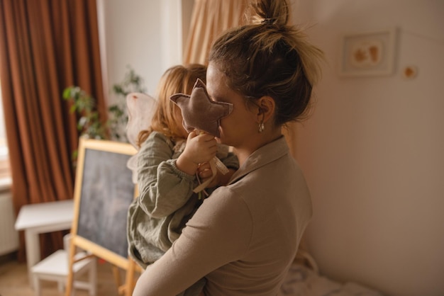 W pokoju szczupła kaukaska kobieta matka trzyma na rękach rudowłosą dziewczynę w wieku 23 lat w pokoju dziecięcym Koncepcja dzieci