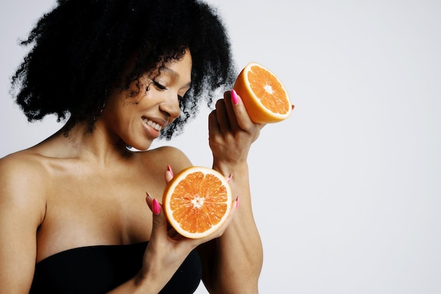 W rękach cytrusowo pomarańczowy grejpfrut Optymista Młoda modelka o wyglądzie afro Zdjęcie