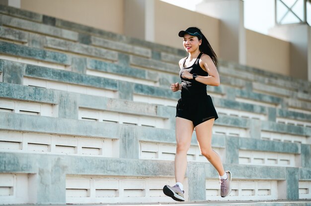 w średnim wieku Beautiful Sport Asian kobieta na zewnątrz lekkoatleta Runner działa na schodach stadionu aktywnego i zdrowego stylu życia.