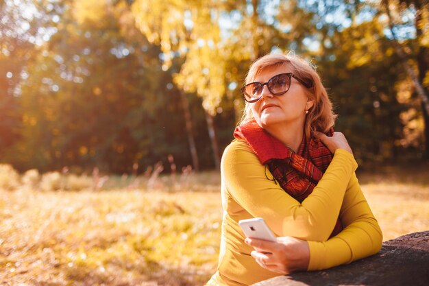 W średnim Wieku Kobieta Relaksuje Używać Telefon Outdoors