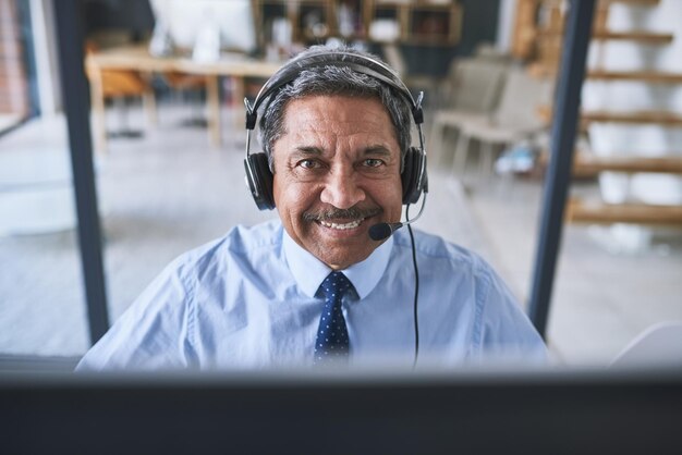 W swoim życiu wykonałem znaczną liczbę telefonów Portret wesołego biznesmena rozmawiającego z klientem za pomocą zestawu słuchawkowego, patrząc w kamerę