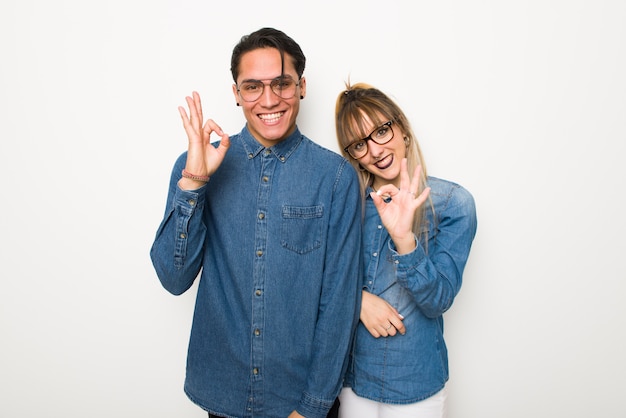 W walentynki Młoda para w okularach przedstawiających znak ok palcami